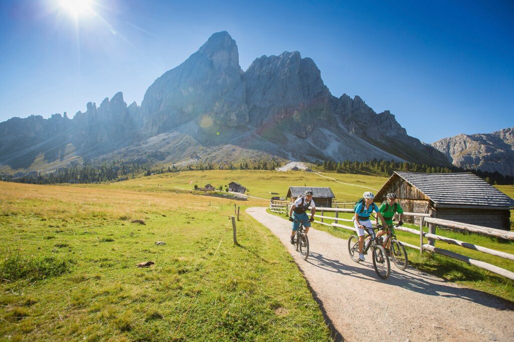 im Vordergrund 3 Mountainbiker und im Hintergrund die Dolomiten