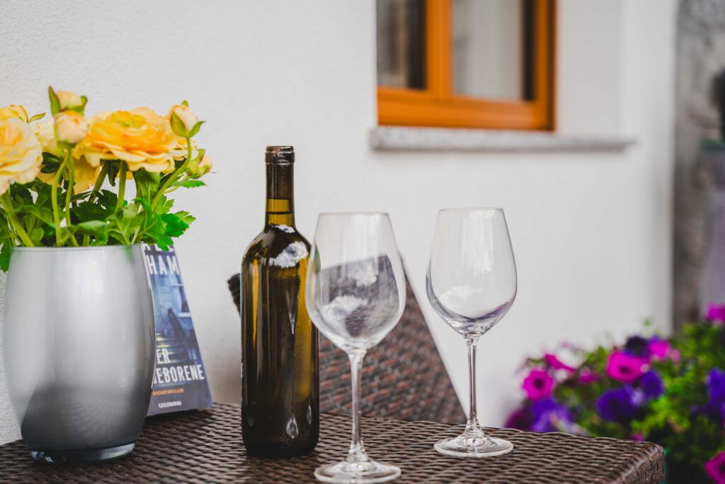Flasche Wein mit 2 Gläsern und Blumen auf einem Tisch